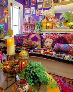 Colorful bohemian living room with patterned pillows, artwork, plants, and eclectic decorations