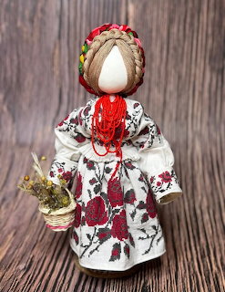 Traditional faceless motanka doll in embroidered dress holding a small basket