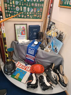 Museum display of sports trophies, medals, shoes, gloves, and protective gear