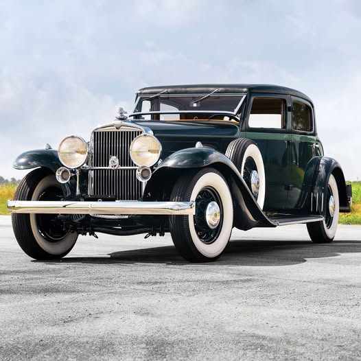 Dark green vintage 1933 Stutz DV-32 Monte Carlo luxury car with white wall tires on pavement