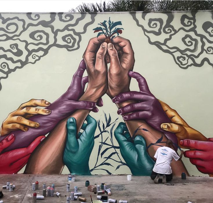 Colorful graffiti mural of multicolored hands holding a plant with swirling clouds on a wall