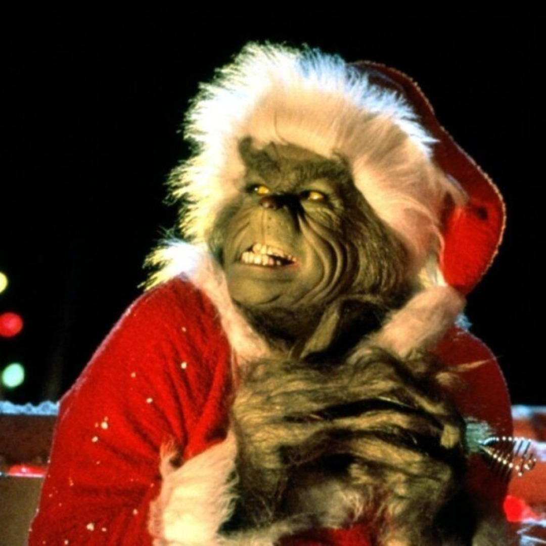 The Grinch in red Santa costume with white fur trim, grinning mischievously
