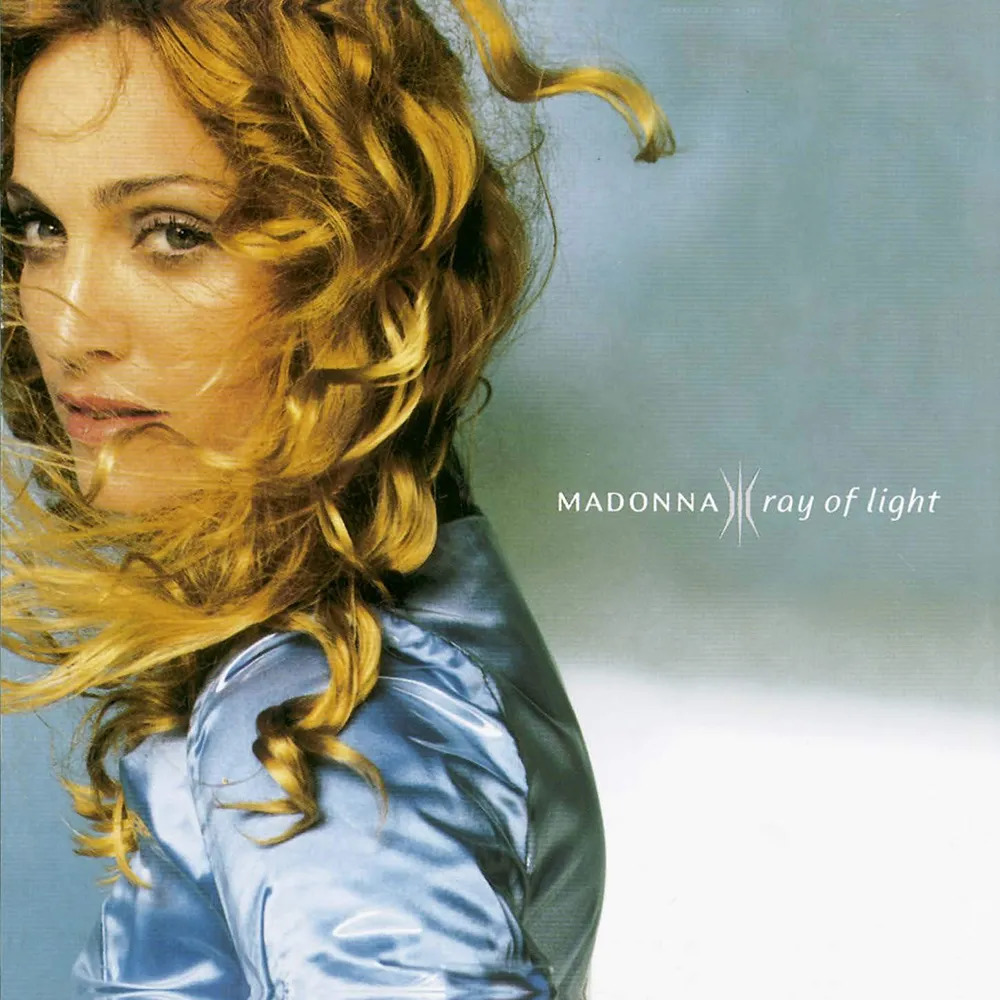 Album cover portrait of Madonna with curly blonde hair and a blue jacket