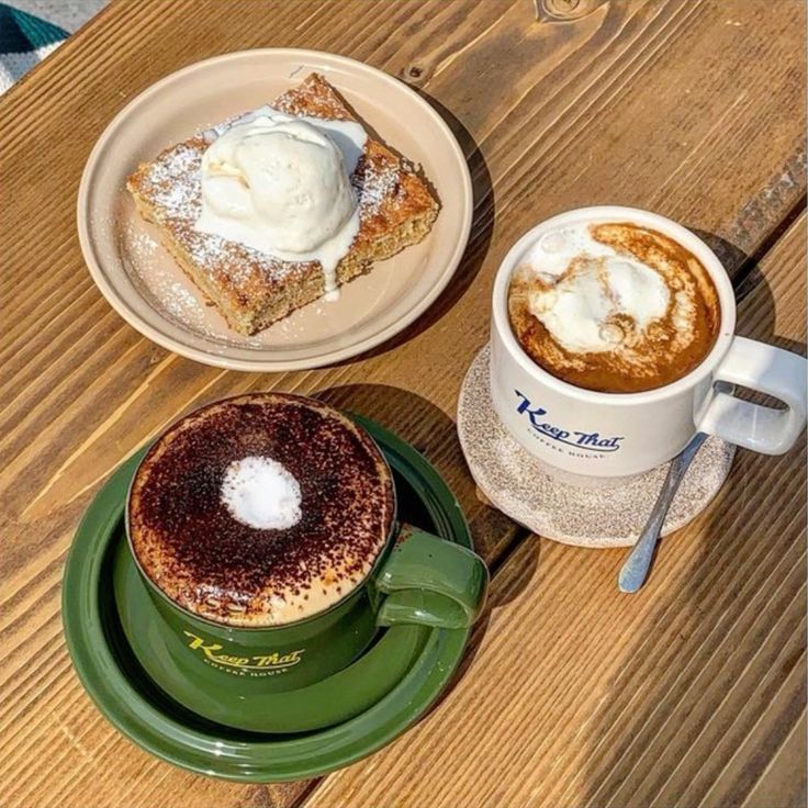 Two coffee cups and desserts on wooden table, including latte art and tiramisu