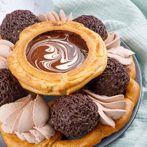 Overhead view of a chocolate tart decorated with truffles and meringue cookies on a plate