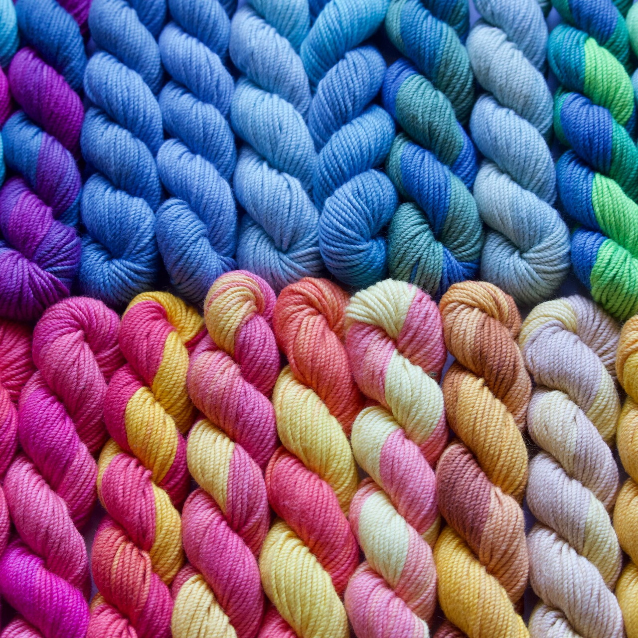 Rows of multicolored twisted cotton yarn skeins arranged in rainbow gradient pattern