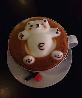 Top view of a coffee cup with 3D bear latte art on a white saucer