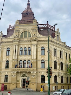 Ornate historic building facade with arched windows and traffic lights on a cloudy day