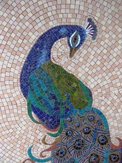 Colorful mosaic artwork of a peacock made from small tiles in blue, green, and teal shades