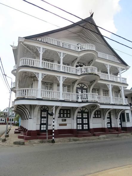 White colonial three-story building with decorative balconies and gabled roof in Suriname