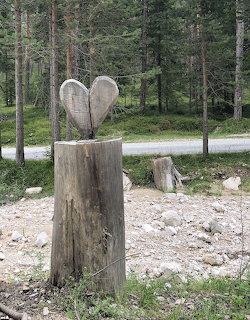 Wooden heart sculpture carved from planks mounted on a tree stump in a pine forest