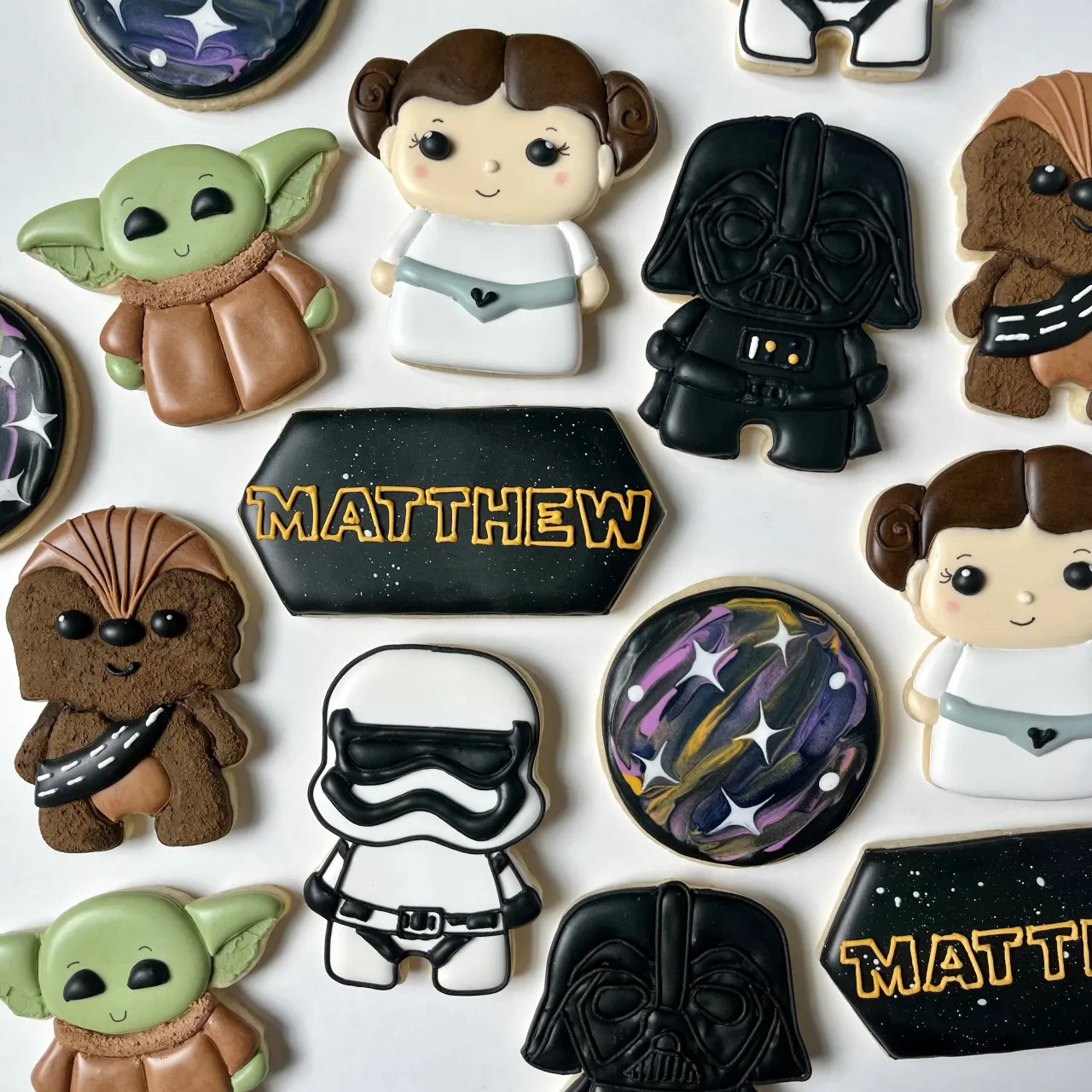 Arrangement of Star Wars themed decorated cookies featuring iconic characters like Yoda, Darth Vader, and Princess Leia