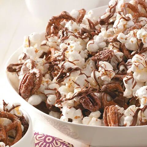 Popcorn drizzled with chocolate and pecans in a white patterned bowl