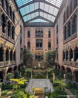Interior courtyard of a museum with arched galleries, glass ceiling, greenery, and mosaic floor