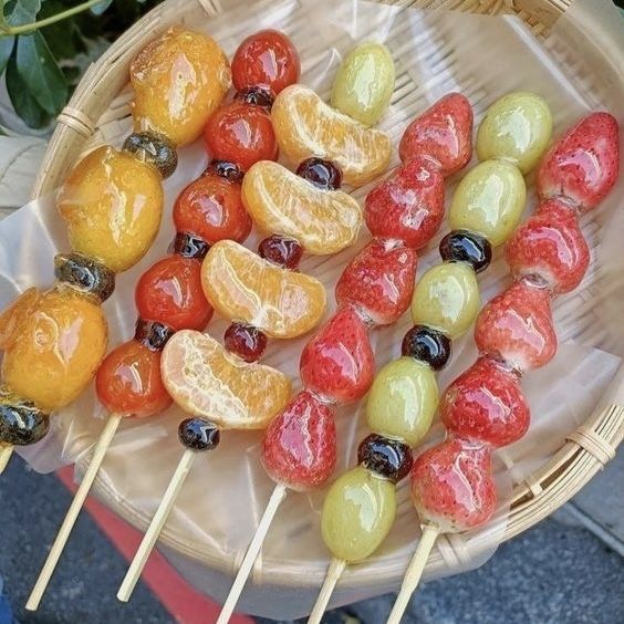 Tanghulu candied fruit skewers with strawberries, grapes, and citrus on bamboo plate