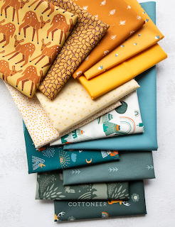 Stack of colorful quilting fabrics folded neatly, featuring orange, yellow, cream and teal patterns