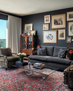 Elegant living room with dark walls, gallery art wall, gray sofa, leopard print chair, and red Persian rug