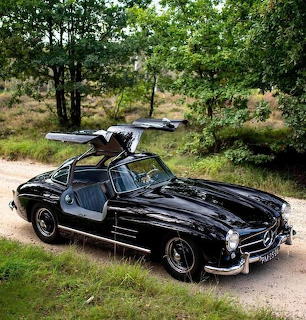 Black Mercedes 300 SL with gullwing doors open on rural road