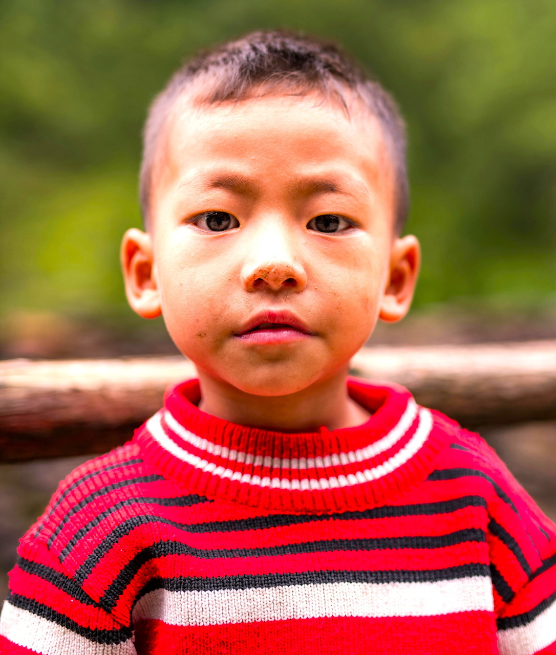 Young boy in a red striped sweater standing outdoors