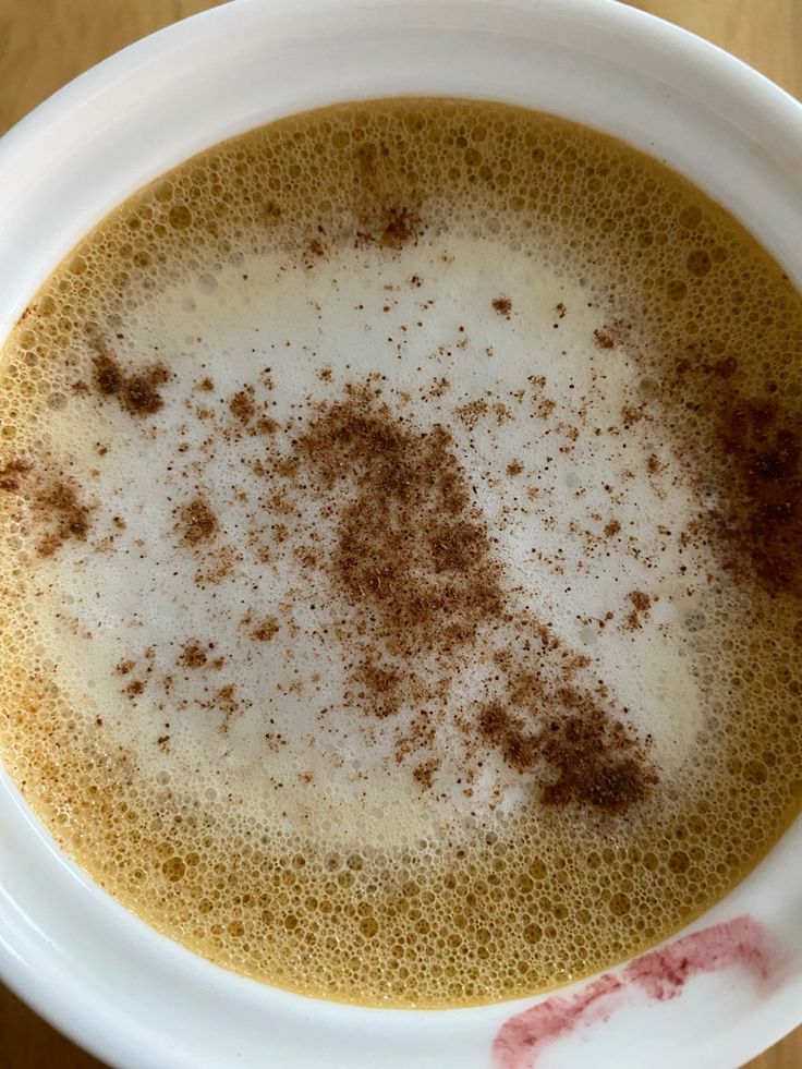 Top view of cappuccino with cinnamon sprinkled on foam in white cup