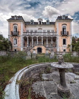 Abandoned ornate mansion with weathered facade, overgrown garden, and empty stone fountain under cloudy sky