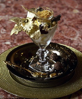 Creamy dessert sundae in a glass goblet with gold leaf garnish on a black plate
