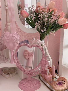 Pink heart-shaped vanity mirror with tulips and baby's breath bouquet on a dreser in a pink room