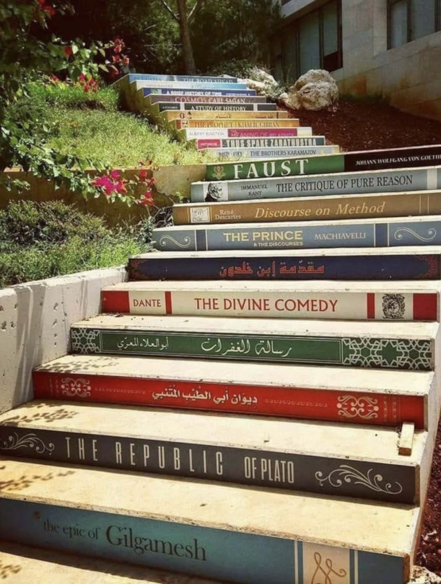 Outdoor stone staircase with steps painted as colorful book spines featuring classic literary titles
