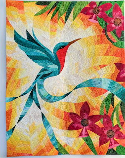 Colorful quilted hummingbird with long tail feathers flying among tropical flowers on geometric patterned background