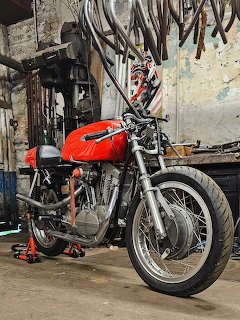 Vintage Harley-Davidson XLR-TT motorcycle with red tank in an old workshop