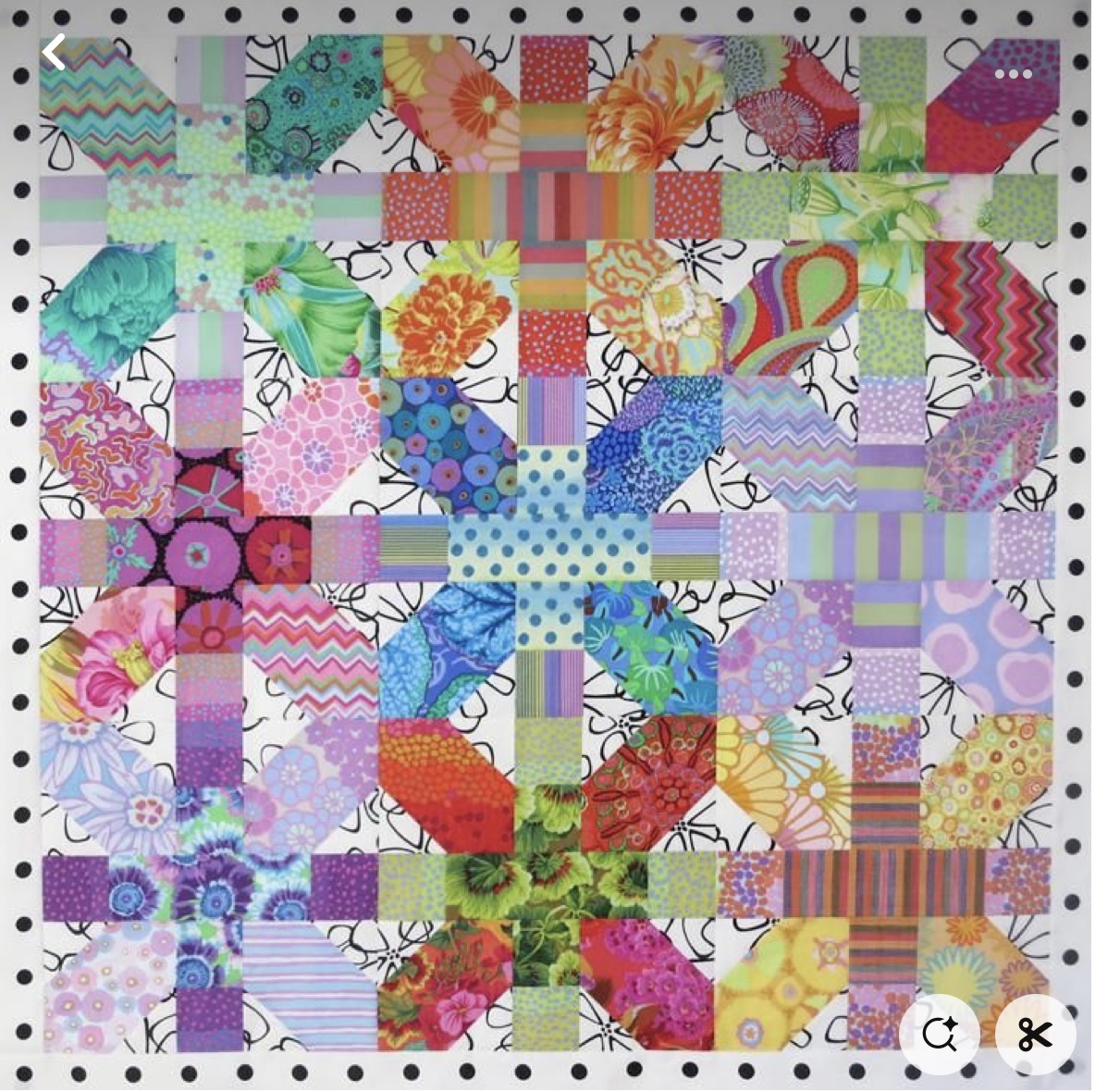 Colorful patchwork quilt featuring cross and plus-sign patterns in geometric fabric squares with varied textures