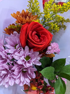 Close-up of colorful flower bouquet with red rose, purple mums, orange and yellow blooms