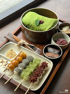 Korean dessert tray with matcha powder bowl, colorful mochi and dango skewers on white plate
