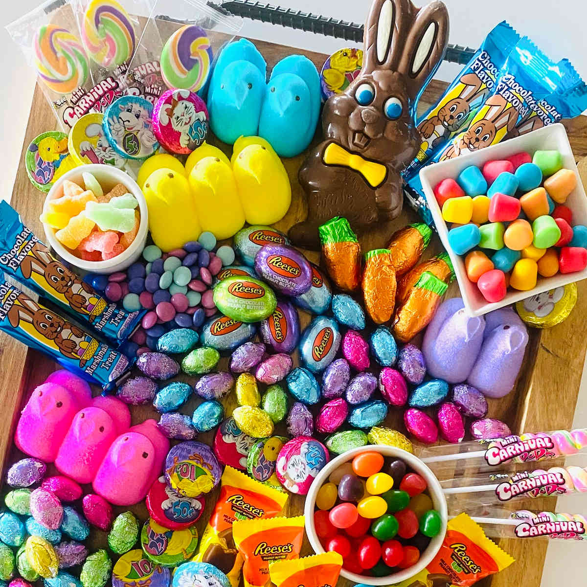 Vibrant Easter candy spread with chocolate bunnies, jellybeans, peeps, lollipops, and colorful sweets on wooden surface