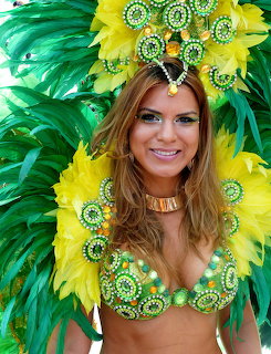 Smiling woman wearing green and yellow feathered carnival headdress and jeweled costume