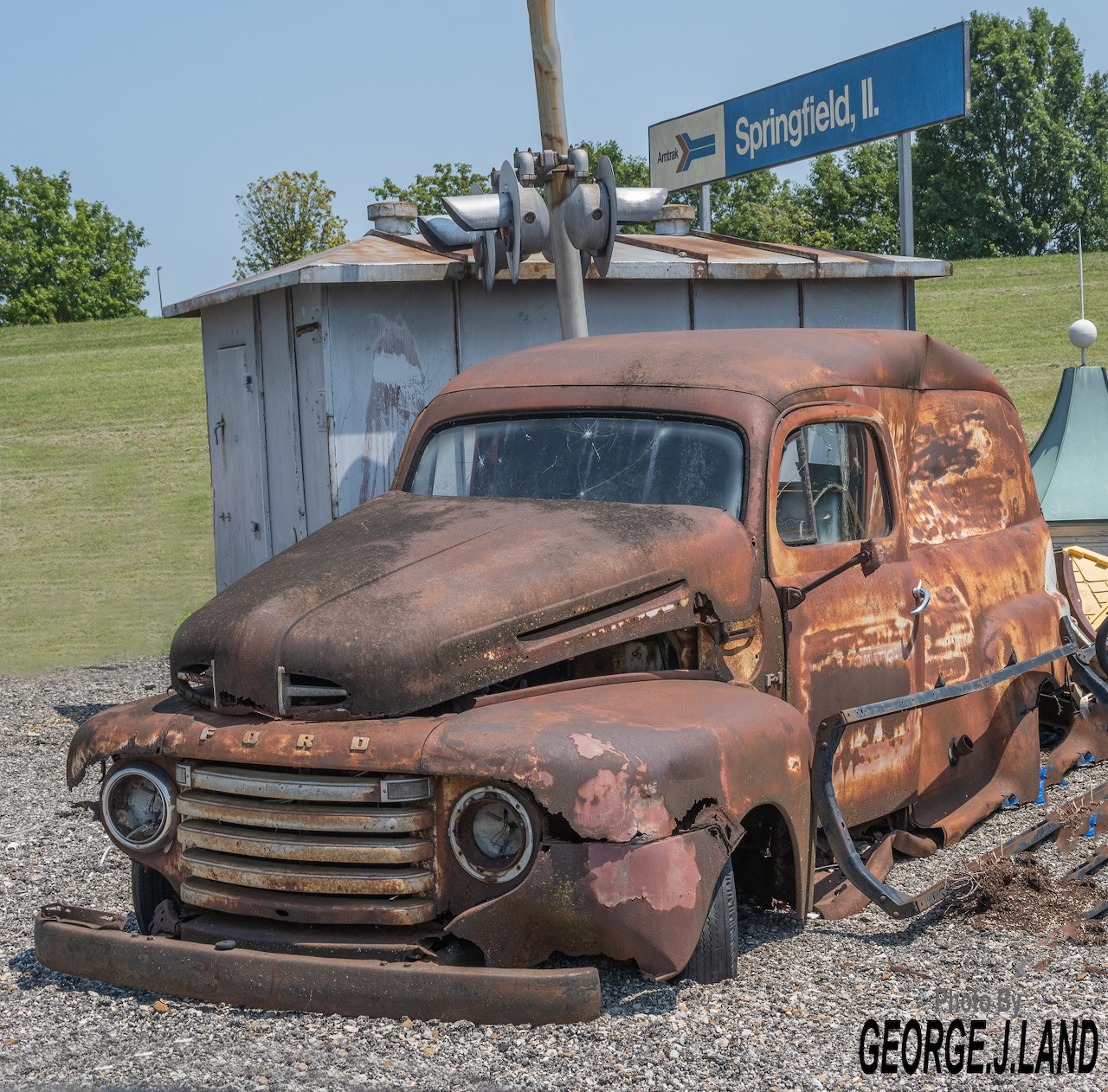 Rusty orange vintage Ford pickup truck parked in front of a blue shed