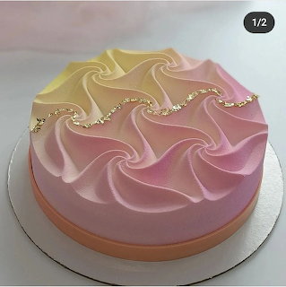 Pastel pink round cake with wave-like swirled frosting and gold accents