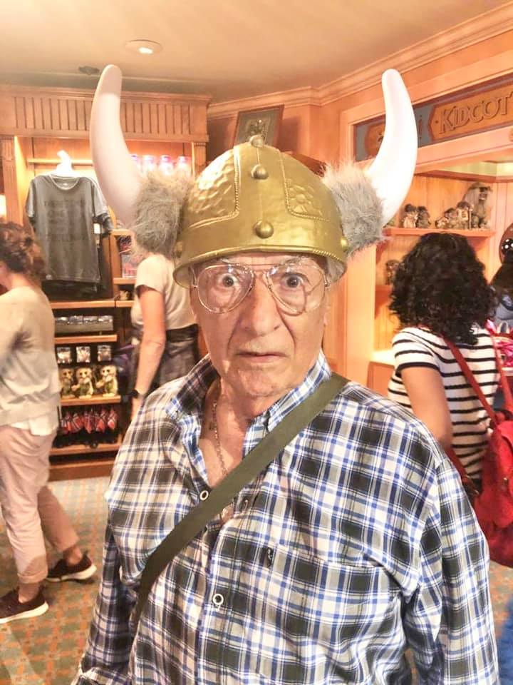 Elderly man wearing a gold Viking helmet with white horns inside a souvenir shop