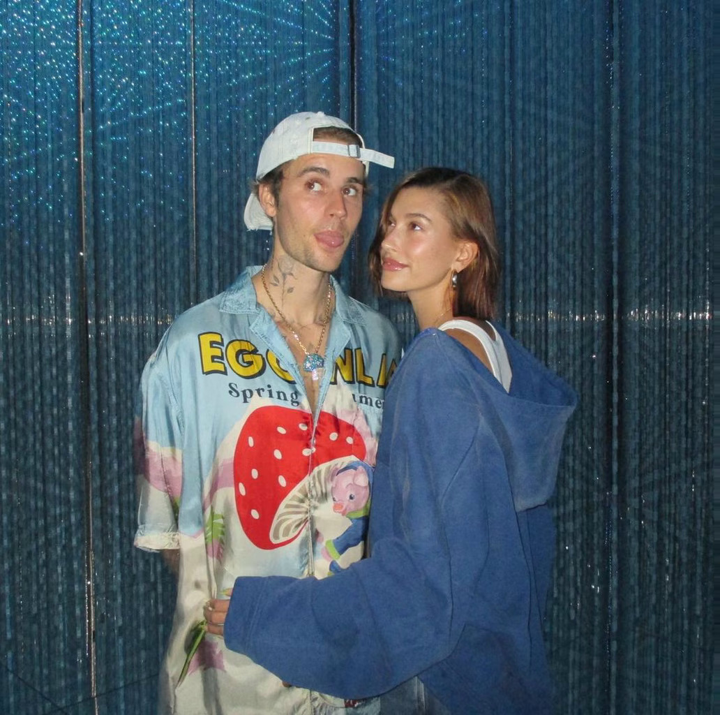 Couple posing together indoors against blue metallic curtain backdrop