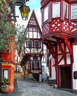 Colorful half-timbered buildings with red frames along a narrow cobblestone aley in a German town