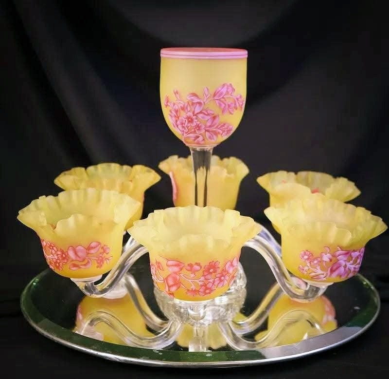 Vintage yellow vaseline glassware with pink floral decoration on a mirrored tray