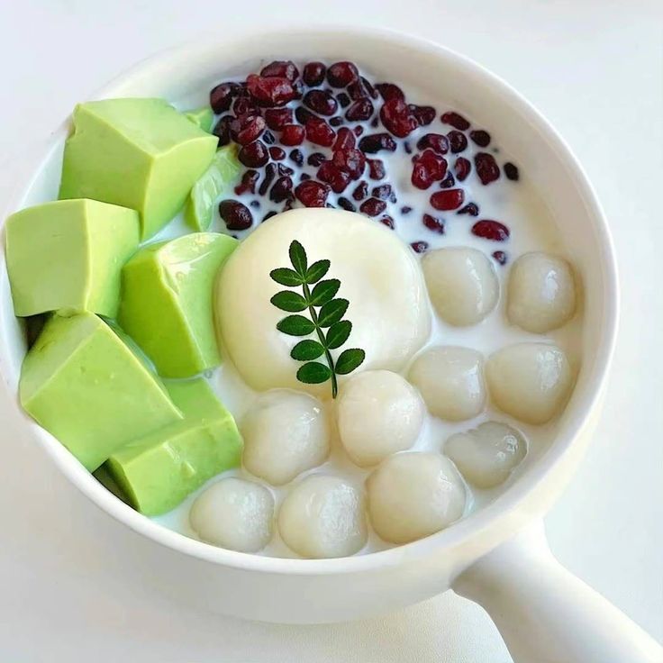 Overhead view of red bean dessert with mochi, green jelly cubes, and red beans in white bowl