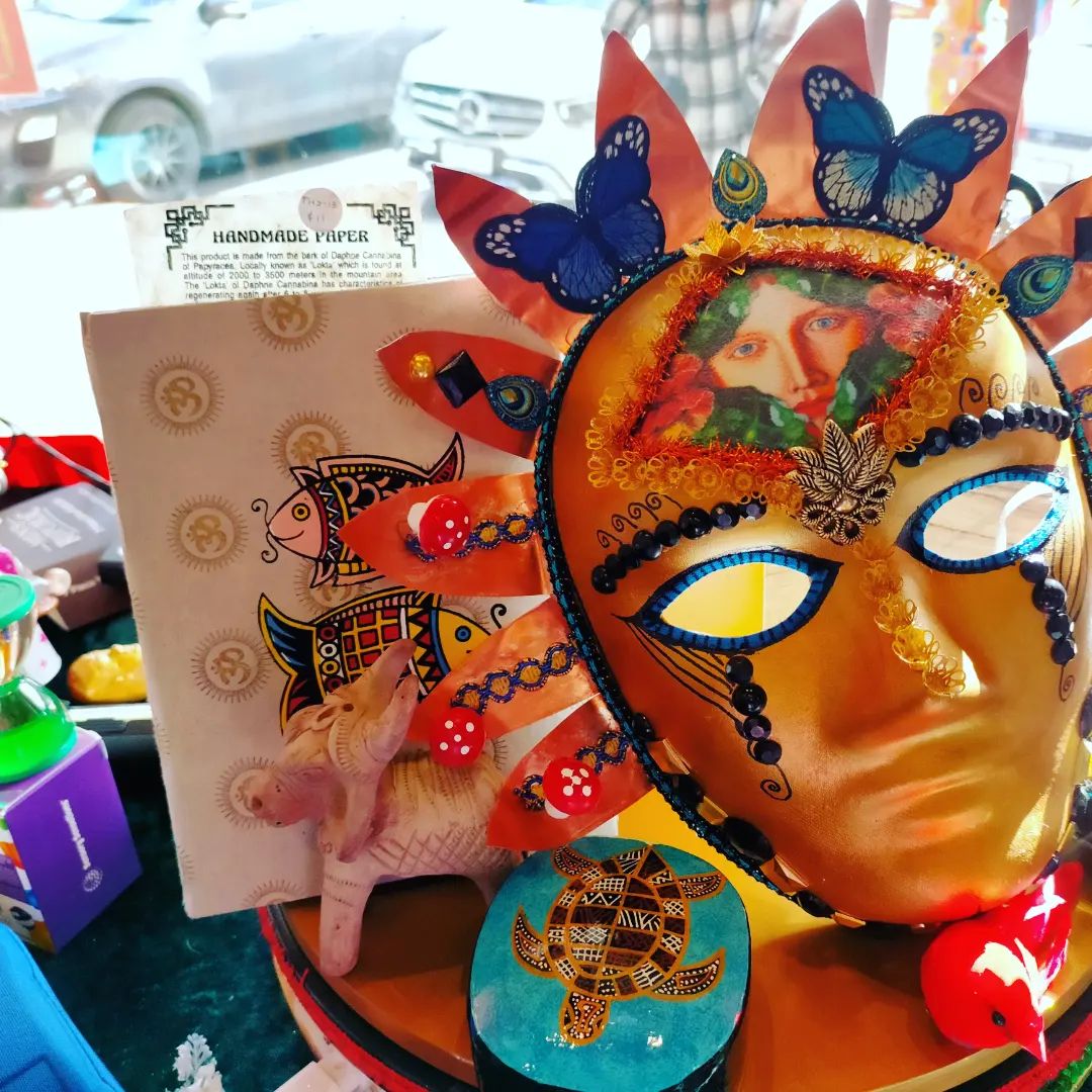 Colorful decorated carnival mask with butterfly accents and painted art pieces on a tabletop