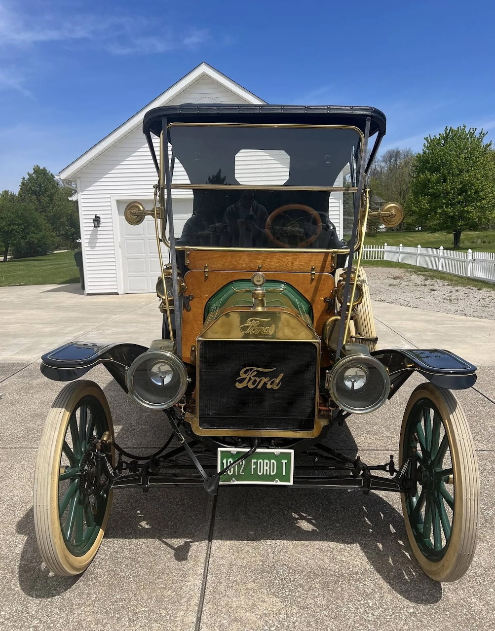 Vintage black Ford Model T car with hood raised, front view, parked outside white building