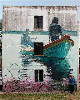 Street art mural on a building wall depicting a boat on water with two figures