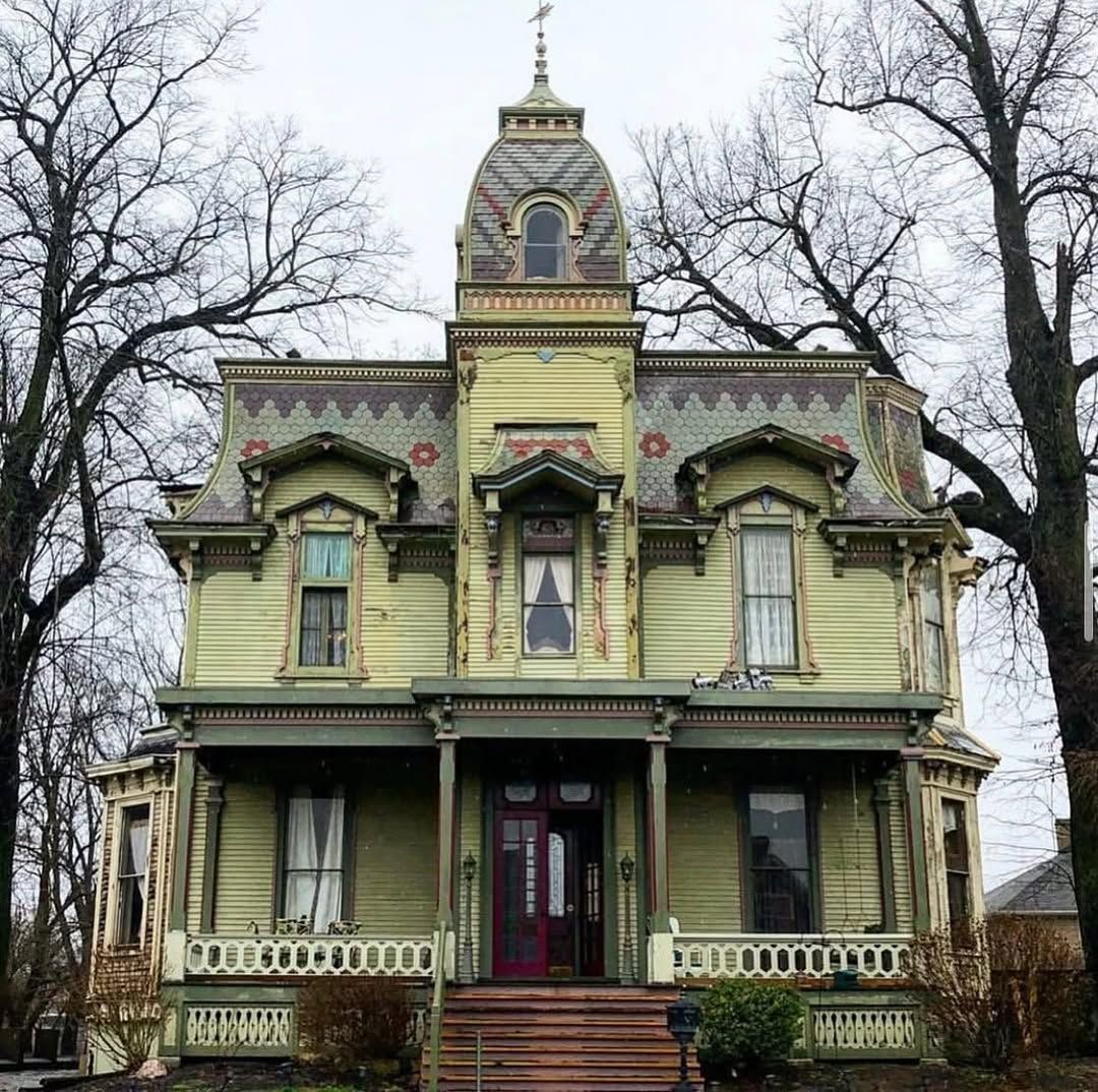 Yellow Victorian mansion with tower and ornate trim in winter