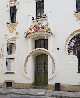 Art Nouveau building entrance with frog sculpture above a green arched door, Frog House Poland