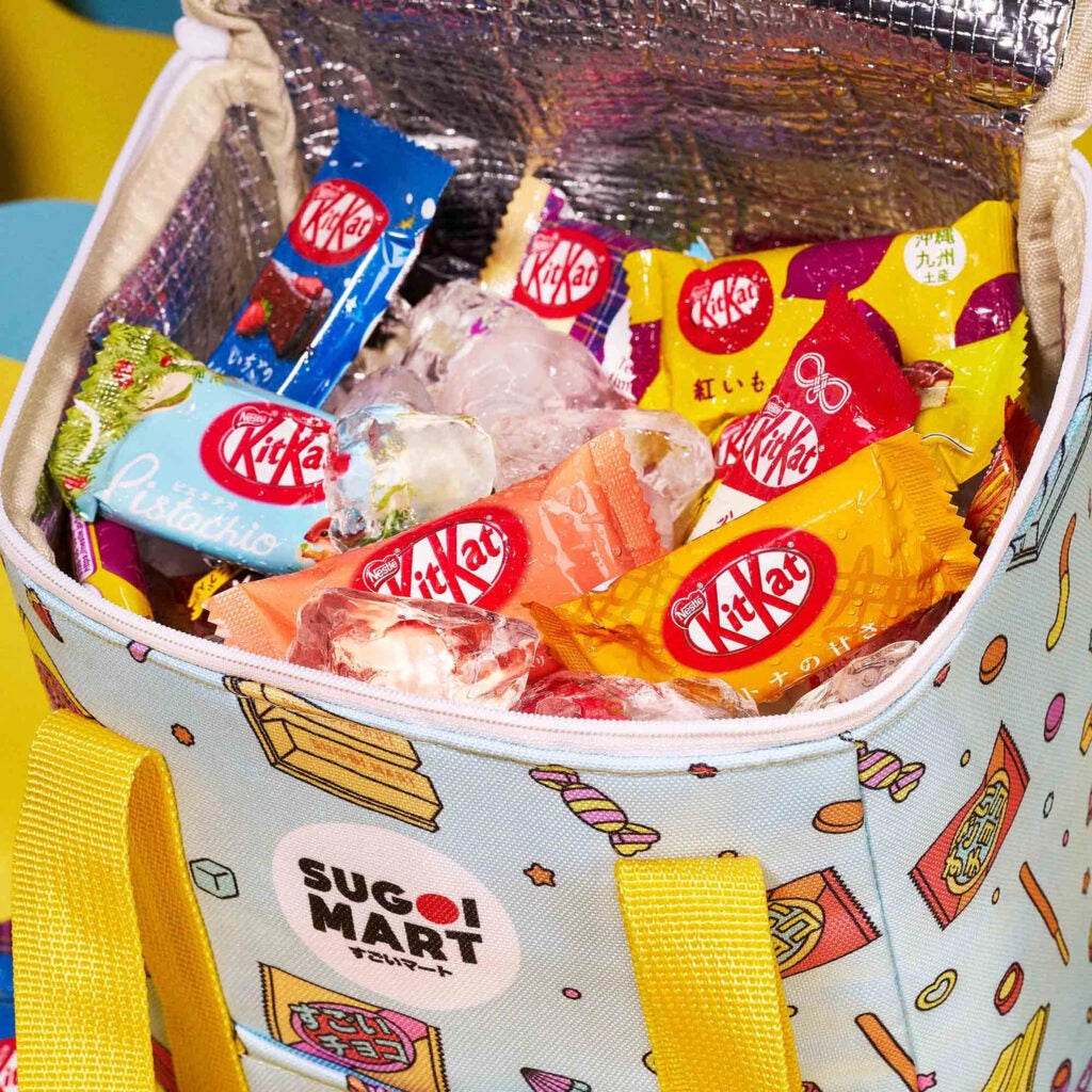 Assorted Japanese Kit Kat candy bars in bright packaging on ice in a white cooler bag