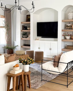 Bright modern living room with white built-ins, arched alcove with TV, iron chandelier, and neutral seating