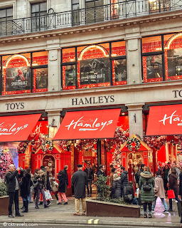 Hamleys toy store facade in London adorned with bright red Christmas decorations and crowds of holiday shoppers